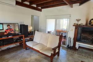 a living room with a white chair and a television at 10.000 m2 Casa de Campo Barrio de Chacra in San Andrés de Giles