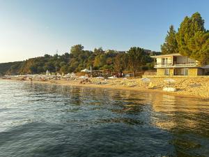 una playa con sombrillas, una casa y el agua en Yulia Guest House, en Ouranoupoli