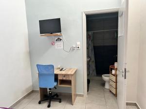 a room with a desk with a television and a blue chair at Lemonia in Megara