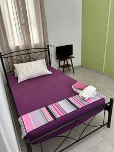 a bed with a purple blanket and a television at Lemonia in Megara