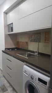 uma cozinha com um lavatório e uma máquina de lavar roupa em Chalet In Solemar, 2br, Elec247, Parking, Wifi em Al Kaslīk