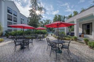 un patio con mesas y sillas y sombrillas rojas en Hampton Inn & Suites Wilmington/Wrightsville Beach, en Wilmington