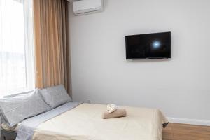 um quarto com uma cama e uma televisão na parede em ReliableHouse квартира в люксовом ЖК возле Меги em Almaty