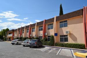 a row of buildings with cars parked in a parking lot at Hotel Sicomoro in Chihuahua