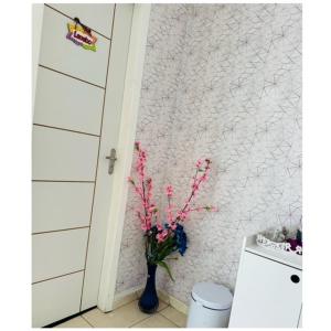 Un baño con un jarrón con flores rosas. en Hostel das Flores en Belém