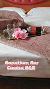 un vassoio con una bottiglia di vino e fiori su un letto di B&B Banatium a Tezze sul Brenta