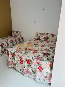 a bed with a floral comforter with two shoes on it at Hostel das Flores in Belém
