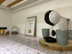 a coffee maker and cups sitting on a table at La Puerta Azul in Jávea