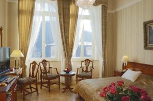 a bedroom with a bed and two windows and chairs at Bristol Palace in Karlovy Vary