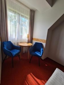 ピブニチュナ・ズドルイにあるSki Hotelの青い椅子2脚、テーブル、窓が備わる客室です。