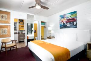 Un dormitorio con una cama blanca y un coche rojo en la pared en The Motor Lodge, en Prescott