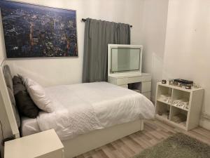 a bedroom with a white bed and a tv at Spacious and homely one bedroom in London