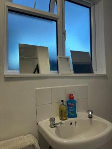 a bathroom sink with a mirror and a window at Spacious and homely one bedroom in London