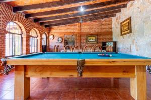 une table de billard dans une pièce avec un mur de briques dans l'établissement Casa De Piedra, à Tequisquiapan