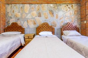 une chambre avec deux lits et un mur en pierre dans l'établissement Casa De Piedra, à Tequisquiapan 53 autres photos