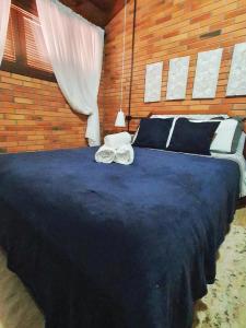 - une chambre dotée d'un grand lit bleu avec des oreillers noirs et blancs dans l'établissement Duplex estilo europeu Ednamar Apartamentos Bérgamo, à Gramado