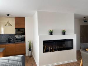 a living room with a white fireplace in a kitchen at Apartament Holiday Amber in Rewal