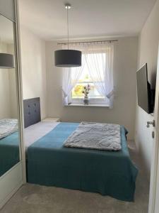 a bedroom with a bed with a mirror and a window at Apartament Holiday Amber in Rewal