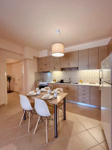 a kitchen with a wooden table and white chairs at Feel at home - Kalamata - Near the center in Kalamata