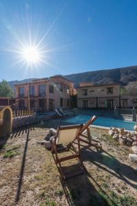 a chair sitting in front of a house with a pool at La Posada del Rio in Tilcara