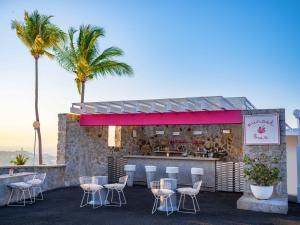 um restaurante com cadeiras e um bar com palmeiras em Las Brisas Acapulco em Acapulco