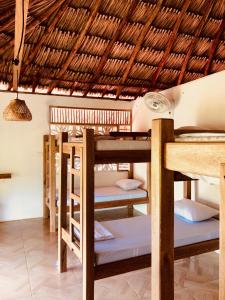 Moñitos的住宿－Maria Moñitos Hostel，一间设有稻草屋顶的客房内的一组双层床