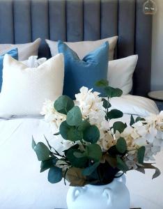 a vase with white flowers on a bed with pillows at Dangerfield Oaks Boutique Cottage's in Mudgee