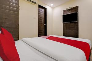 a bedroom with a bed with red pillows and a television at OYO Flagship Hotel Accore Inn in Mumbai