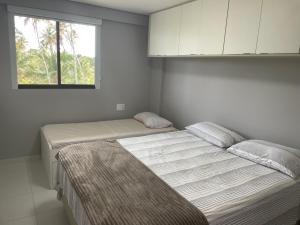 a bedroom with two beds and a window at Flat Confort Pé na Areia in Ipojuca