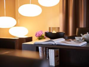 Victoria - Alpine Boutique Hotel & Fine Dining في ميرينغين: a book sitting on a table with lights and a table sidx six