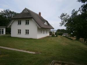 ein weißes Haus auf einem grünen Feld in der Unterkunft Ferienhaus der Winde in Groß Stresow