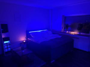 a dark room with a bed with a blue hue at Relax Oasis with 65 SmartTV, Kitchen and Balcony in Duisburg +6 photos