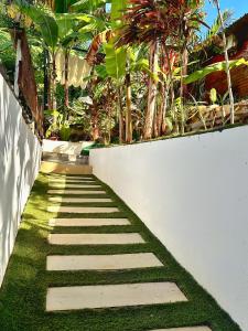 a pathway with grass and a white wall at LESSENCIEL Villa in Sada