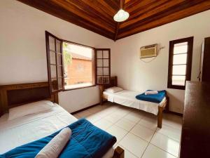 a room with two beds and two windows at Casa Aconchegante - Com Passeio de Escuna de Cortesia! in Paraty