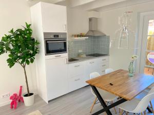 a kitchen with white cabinets and a wooden table at Thuishaven in Vlissingen
