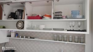 a kitchen shelf with glasses and a clock on it at Estilo Bela Vista 308 in Cabedelo