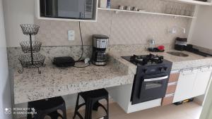 a kitchen with a stove and a counter with stools at Estilo Bela Vista 308 in Cabedelo