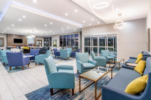 La Quinta Inn & Suites by Wyndham Valdosta في فلدوستا: غرفة انتظار مع كراسي وطاولات زرقاء