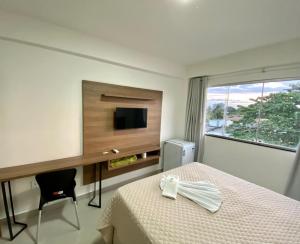 a bedroom with a bed and a desk and a television at Hotel Skalla in Teixeira de Freitas