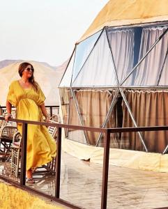 a woman in a yellow dress standing in front of a tent at Wadi rum Ahmed Badawi in Wadi Rum