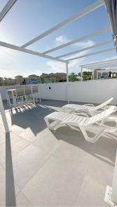 een patio met witte stoelen en een witte parasol bij Casa Leyen Penthouse with rooftop pool and stunning view and 3 big private terraces in Orihuela