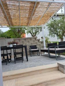 un patio con sillas, mesa y bancos en Villa The Green Door - Casa Vacanze vicino a Roma, en Fonte Nuova