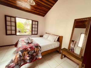 a bedroom with a bed and a mirror at Casa Aconchegante - Com Passeio de Escuna de Cortesia! in Paraty