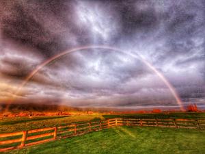 a rainbow in the sky over a field with a fence at housewithnonails in Matamata