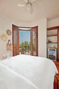 a bedroom with a large white bed and a window at La Villa Luz (sólo adultos) in Zihuatanejo +84 photos