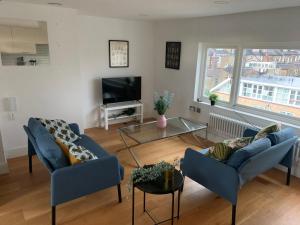 a living room with two blue couches and a tv at Delightful new ensuite bedroom with stunning shared kitchen & living room -1C The Charteris in London