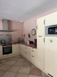 una cocina con armarios blancos y un reloj en la pared en Maison en vallée d’Ossau, en Sainte-Colome