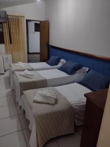 a row of four beds in a room at Pousada A Pérola in Rio de Contas