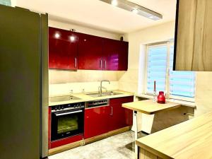 una cocina con armarios rojos y fregadero en Wie Zuhause! Wohnung mit Garten, en Forstinning