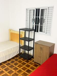 a bedroom with a black book shelf next to a bed at Quarto privativo ótima localização in São Paulo
